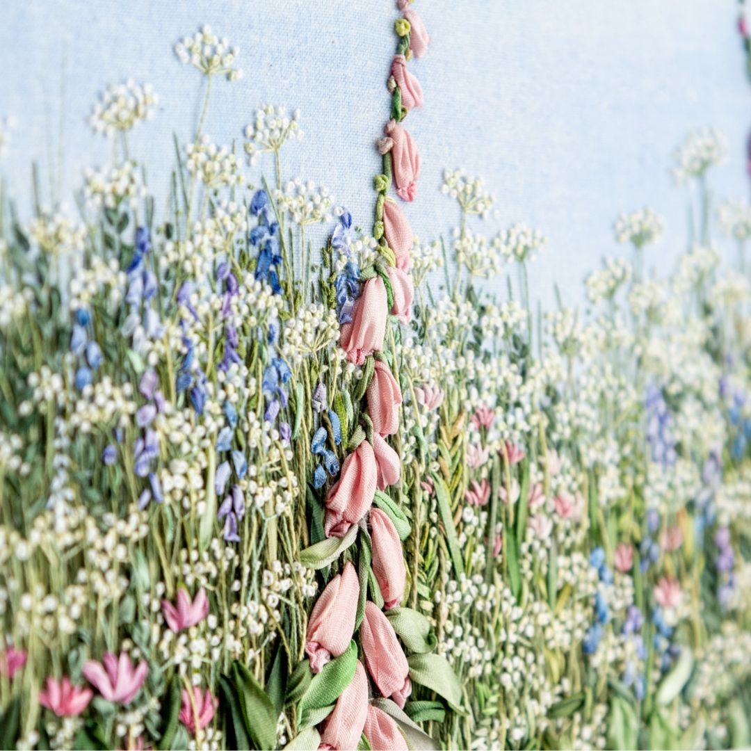 close up of a pink foxglove spire amongst the cow parsley and other meadow flowers
