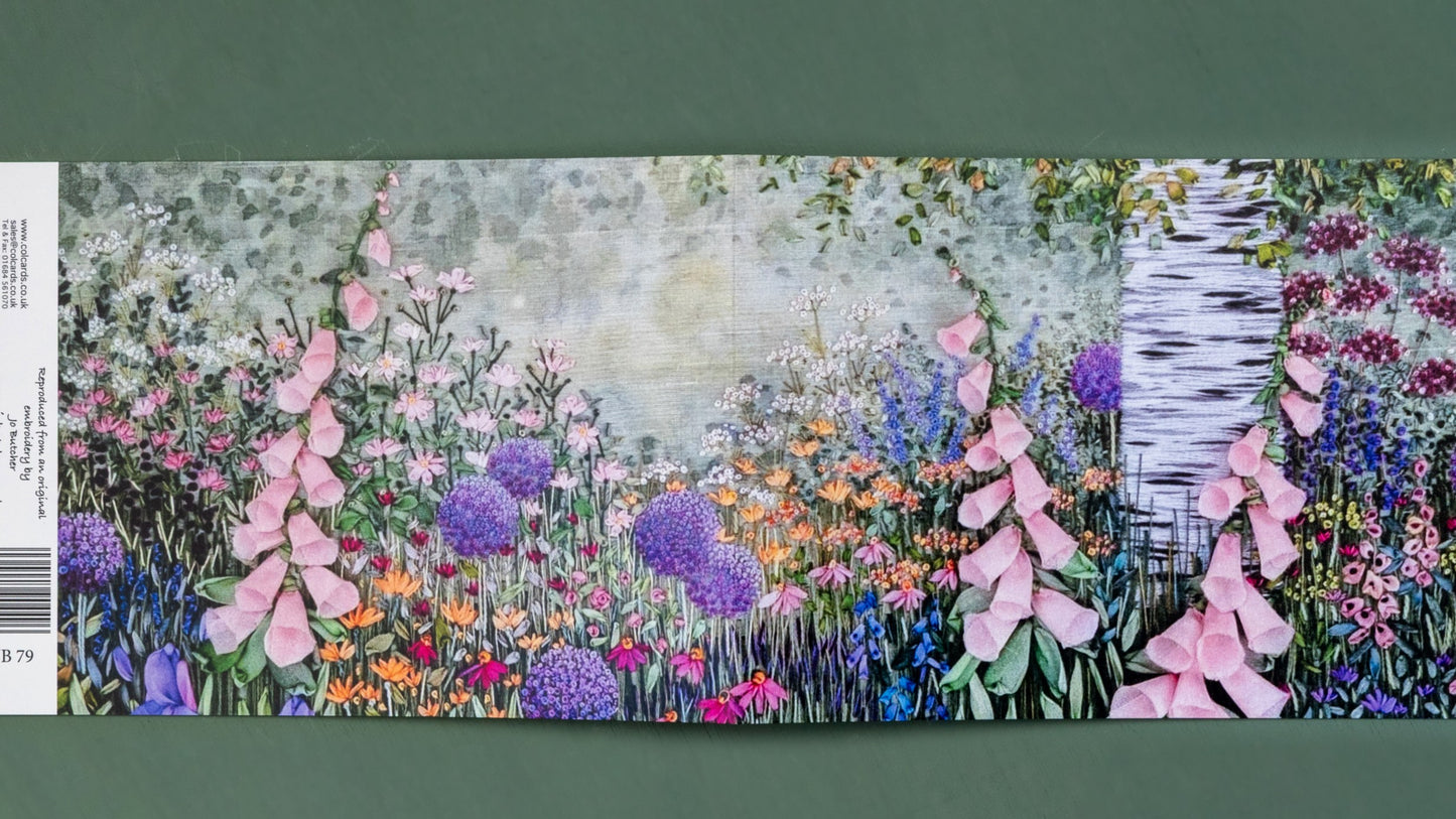 An open card showing the front and back image of a hand embroidered trunk of a silver birch tree. Under the tree is a flower border filled with a range of flowers in full bloom.