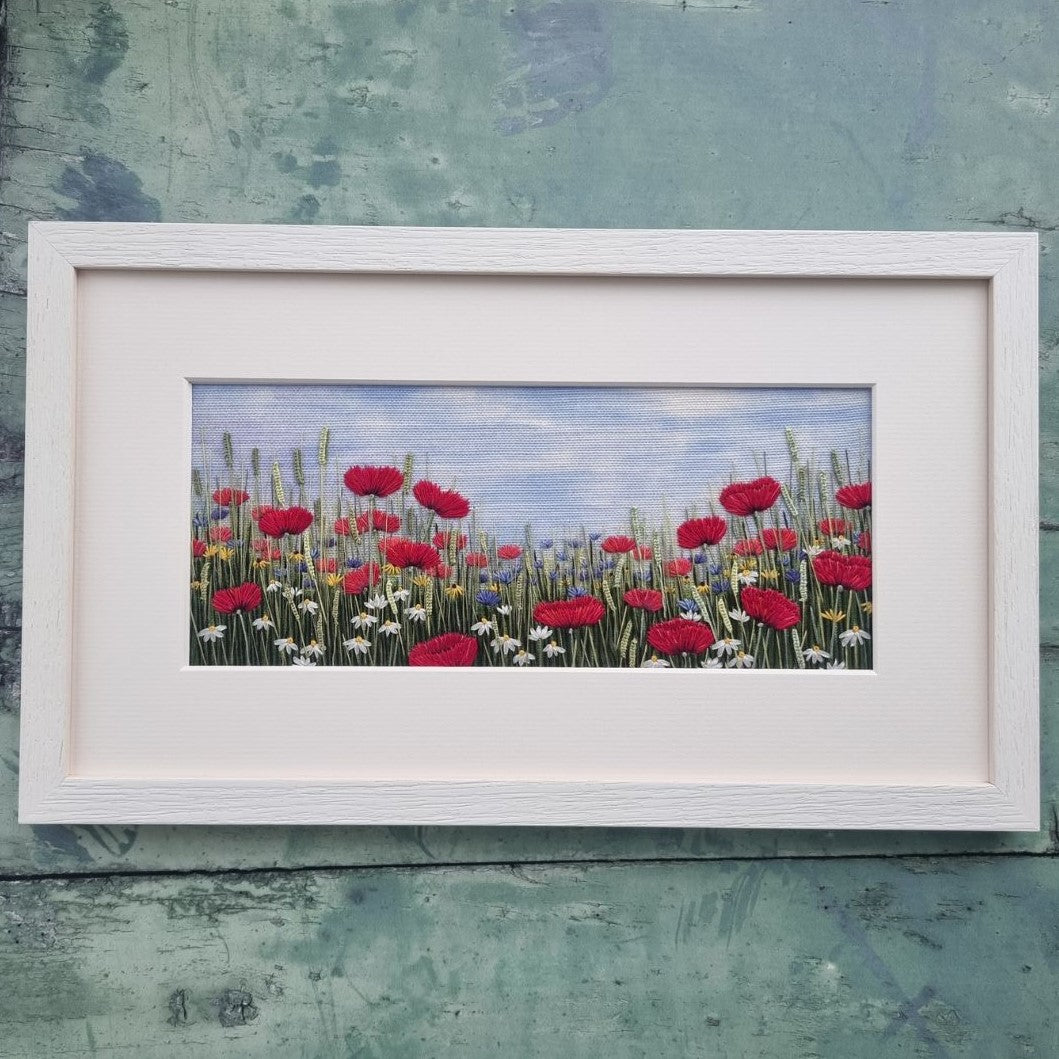 a white landscape mount and frame containing the finished embroidery kit 