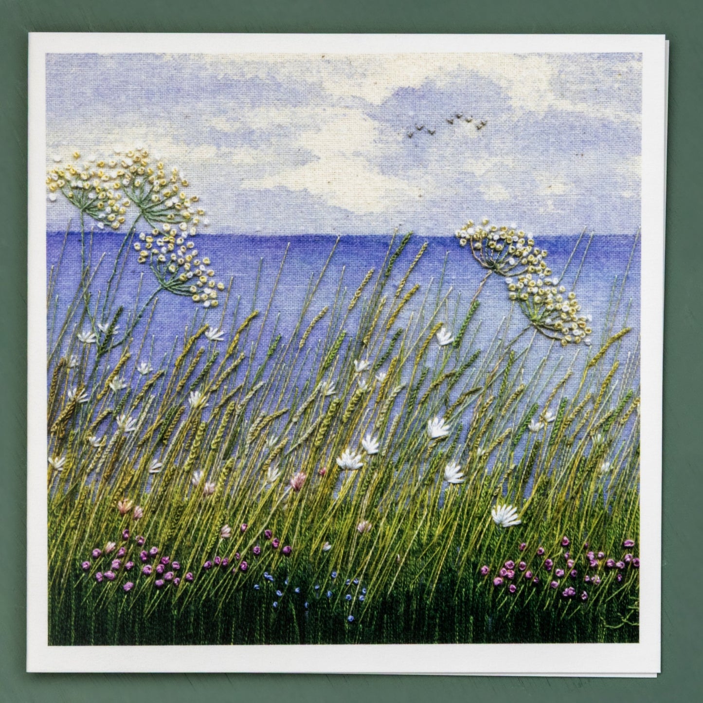 A painted background of the horizon with hand embroidered foreground grasses and flowers all slightly leaning to the left in the coastal breeze.