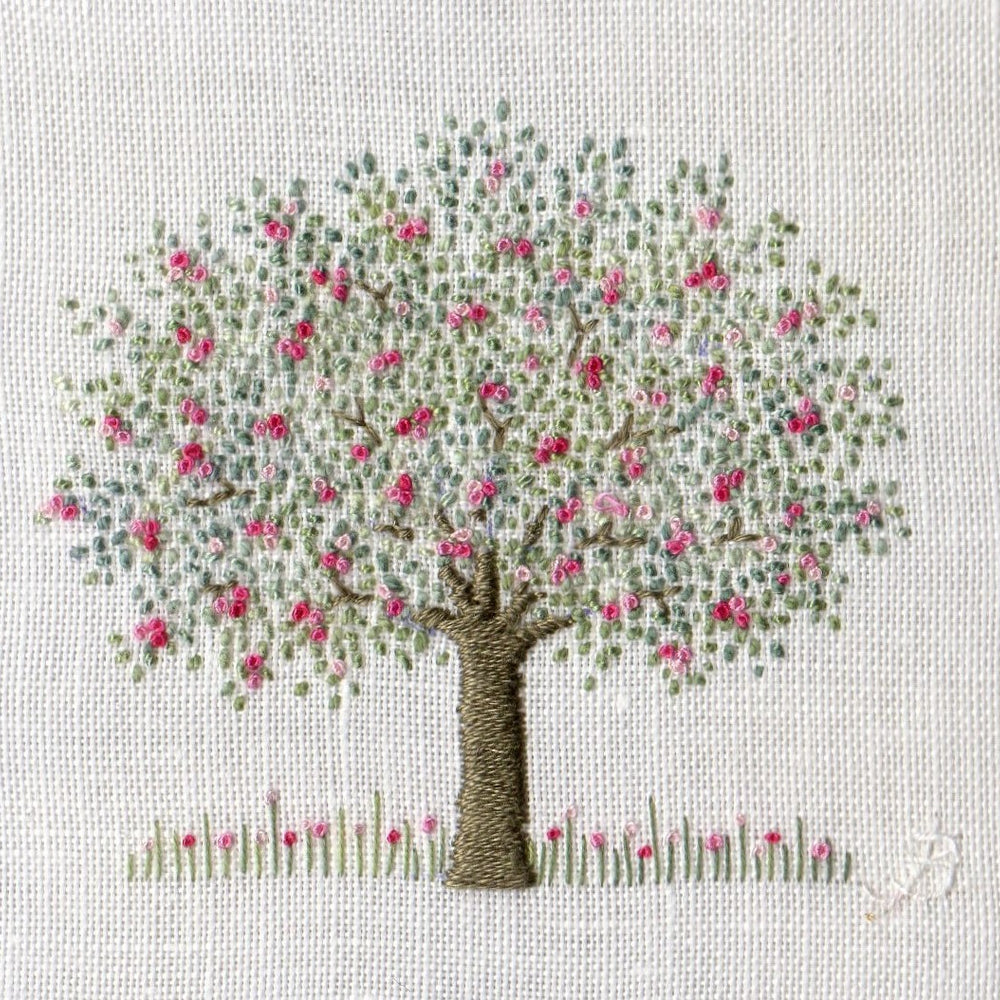 Simple hand embroidered apple tree with pink blossom on a white linen background