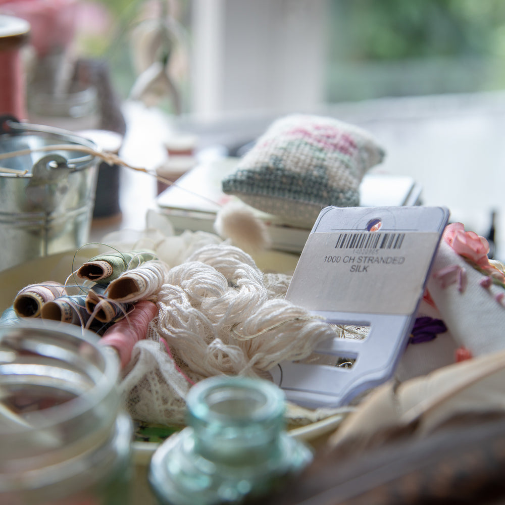 collection of threads, glass pots and other items staged for photo